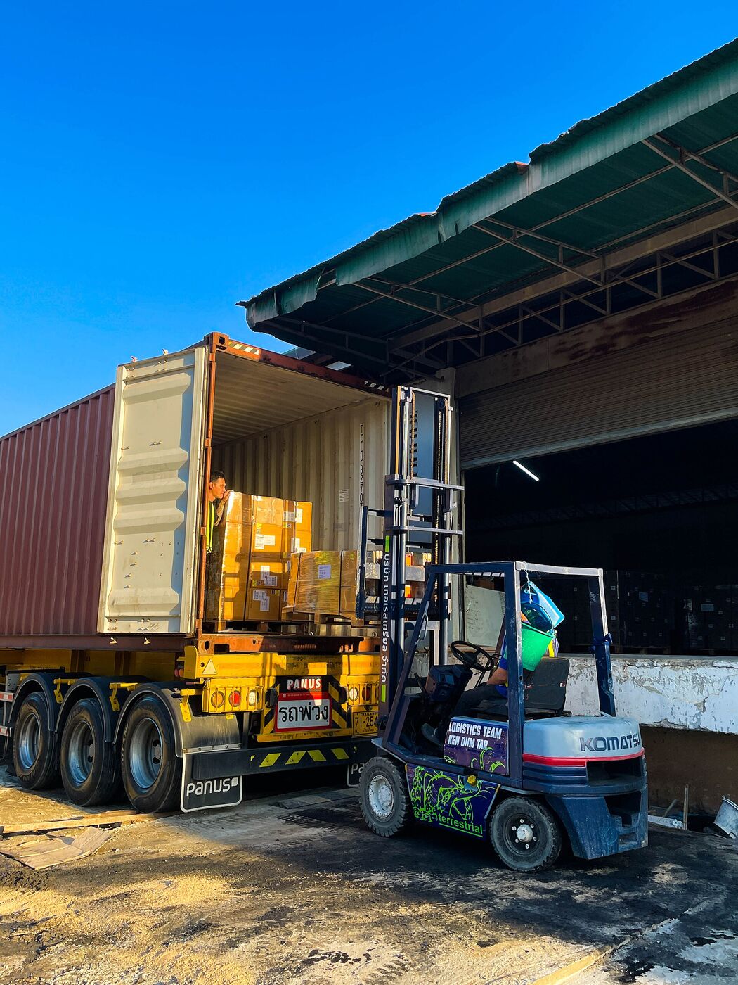 A forklift loading a shipping container from a warehouse dock