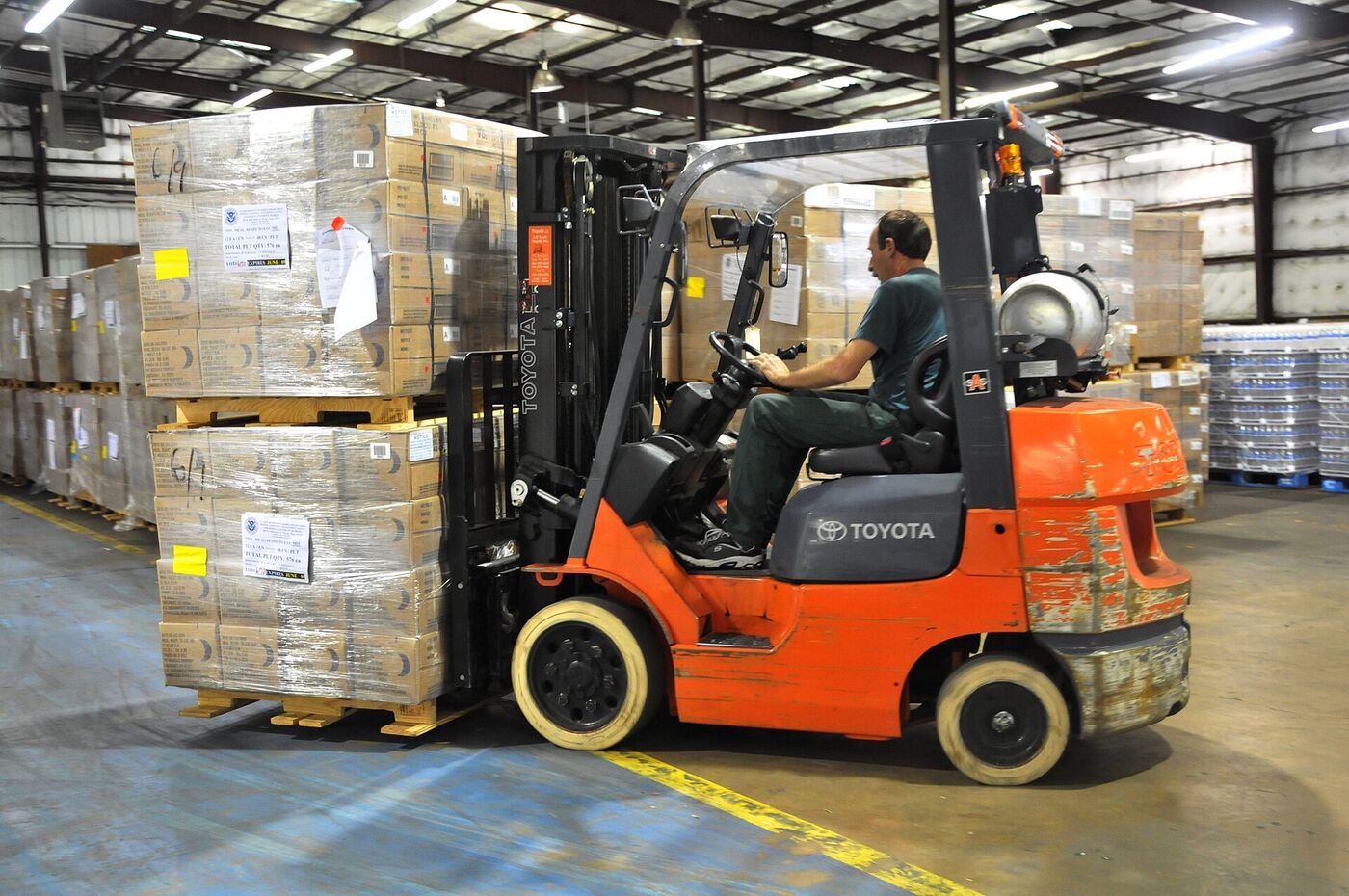 A forklift moving pallets in a busy warehouse