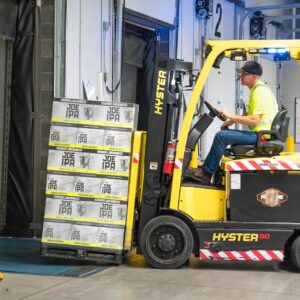 man riding a yellow forklift lifting boxes