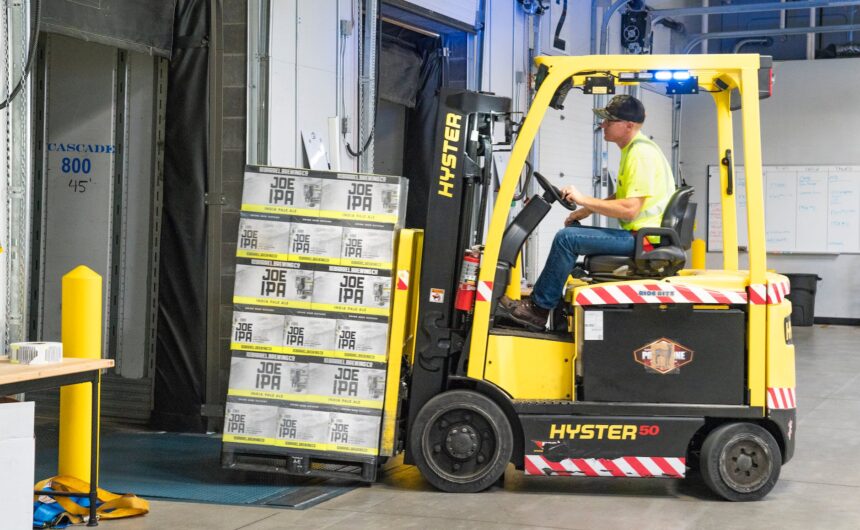 man riding a yellow forklift lifting boxes