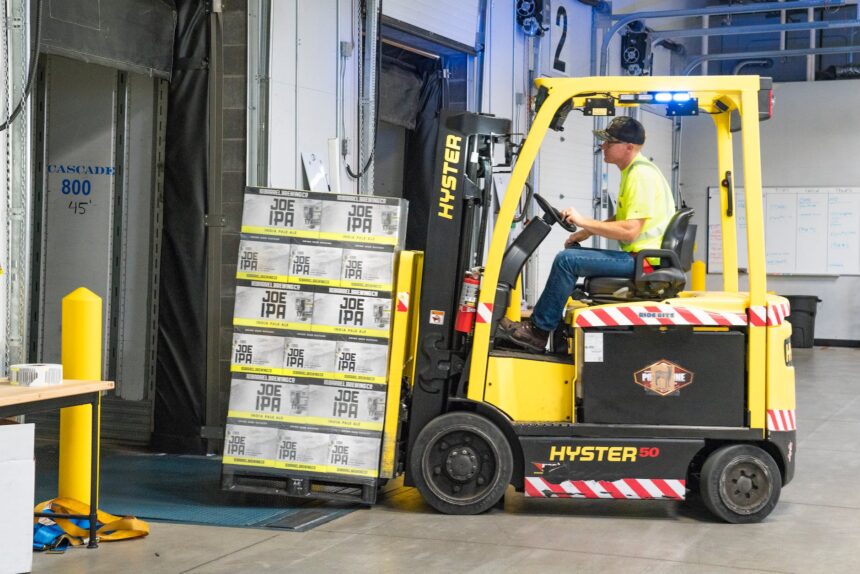 man riding a yellow forklift lifting boxes